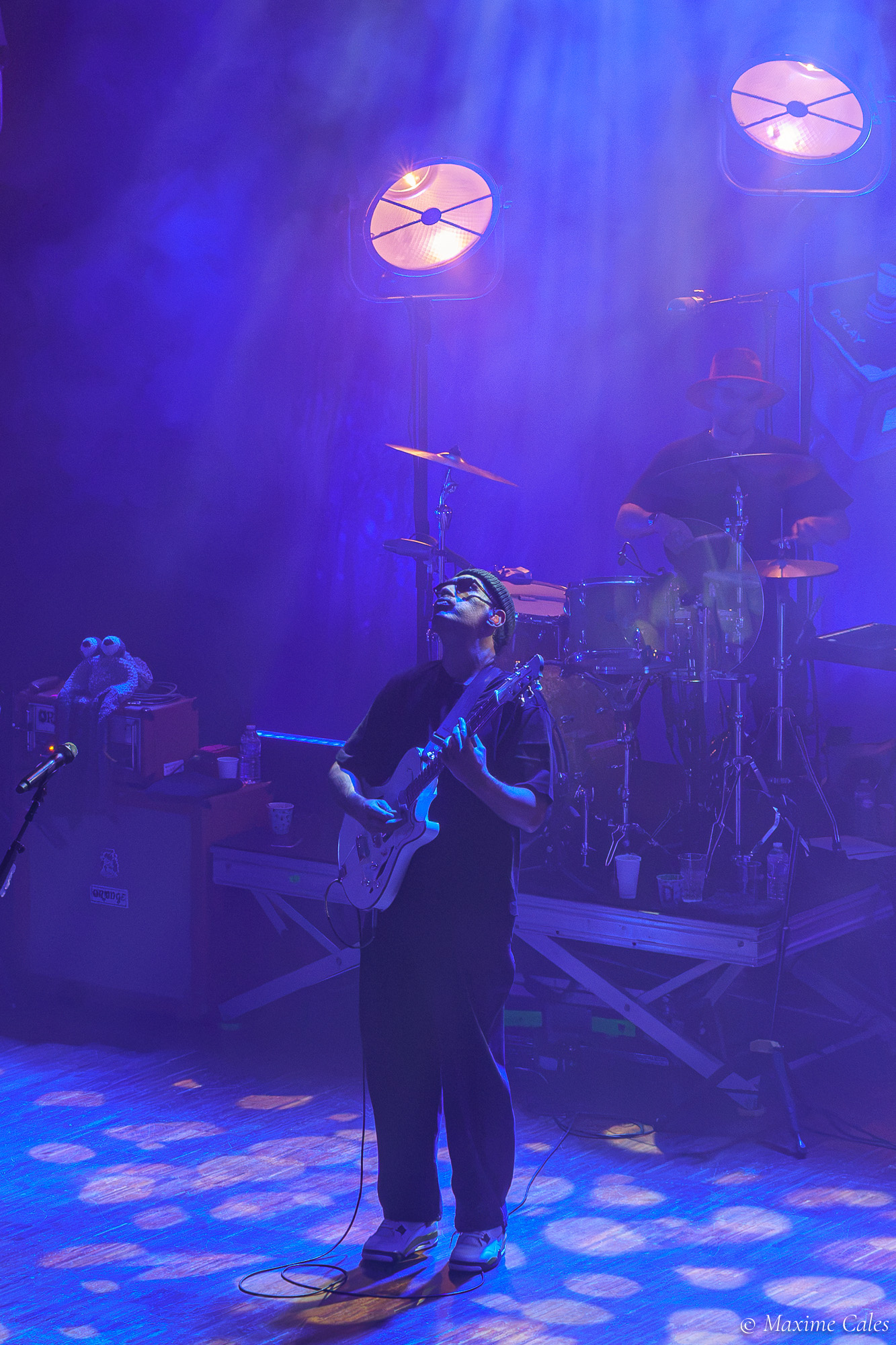 Guitariste seul sous les projecteurs ronds, lumière bleue, concert de Fat Freddy's Drop